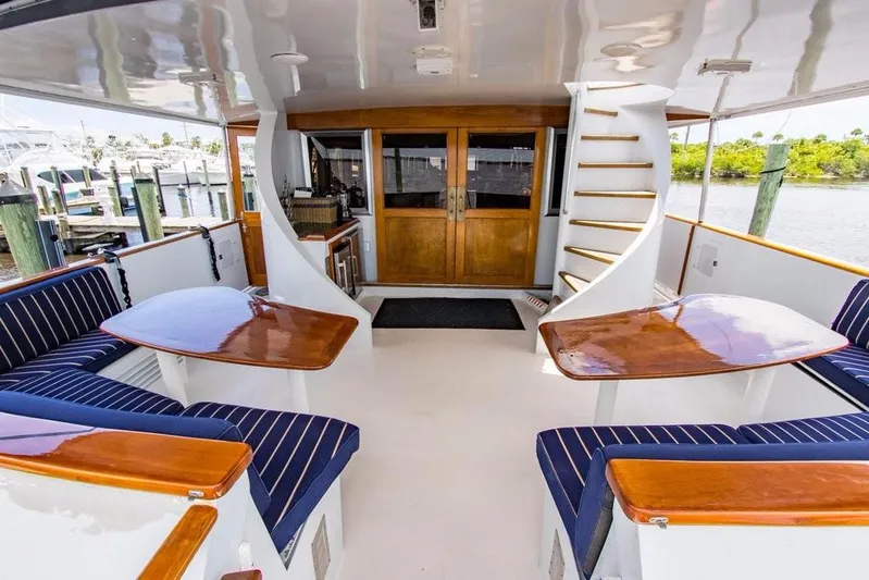 Timeless Yacht Photos Pics Outdoor seating area on 1983 Benetti Custom Lloyds M.Y. yacht with wooden tables and blue cushions.