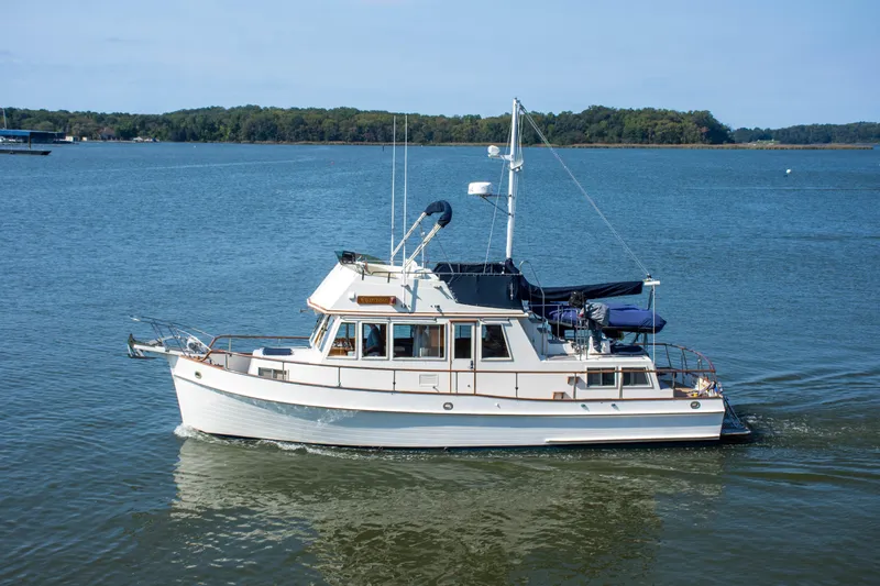  Yacht Photos Pics 1990 Grand Banks 36 Classic yacht cruising on a serene lake with forested shoreline.
