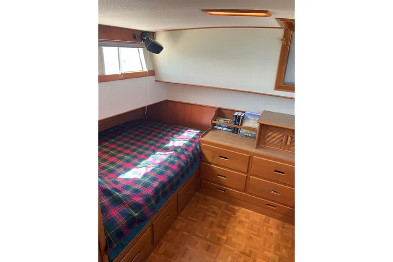  Yacht Photos Pics Cozy cabin interior of 1990 Grand Banks 36 Classic with plaid bedding and wooden storage.