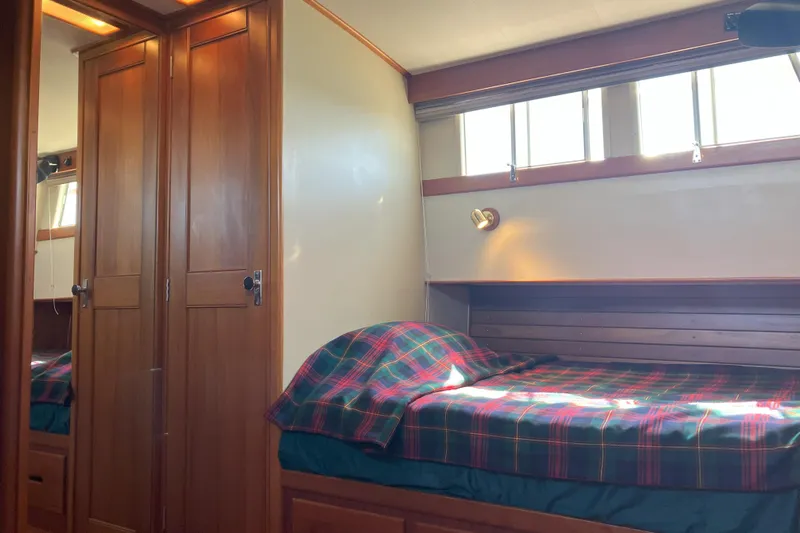  Yacht Photos Pics Cozy cabin interior of 1990 Grand Banks 36 Classic with plaid bedding and wooden cabinetry.