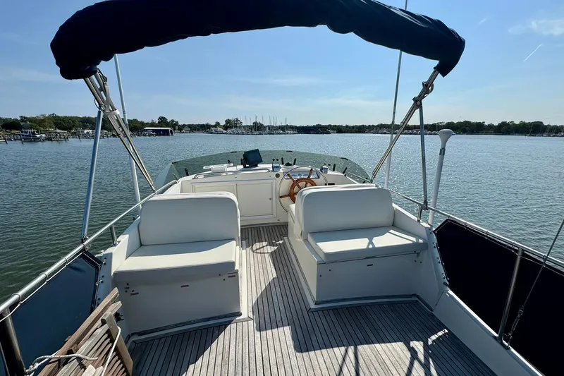  Yacht Photos Pics 1990 Grand Banks 36 Classic yacht deck with seating and steering wheel, overlooking calm waters.