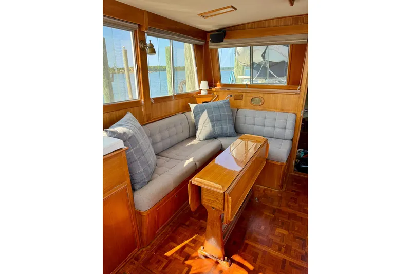  Yacht Photos Pics Cozy interior of 1990 Grand Banks 36 Classic yacht with cushioned seating and wooden table.