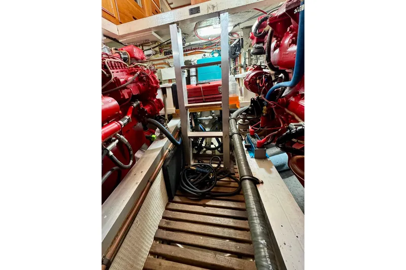  Yacht Photos Pics Engine room of a 1990 Grand Banks 36 Classic with red machinery and wooden flooring.