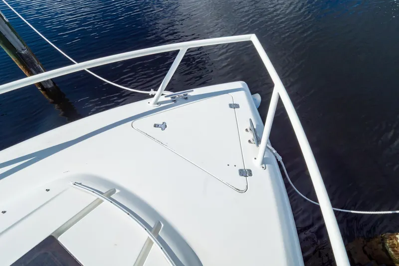  Yacht Photos Pics Bow of 2003 Intrepid 370 Cuddy boat with railing and hatch, docked on calm water.