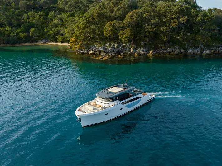 Bgx63 Yacht Photos Pics 2024 Bluegame BGX63 yacht cruising near a lush, forested shoreline.