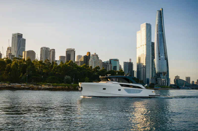 Bgx63 Yacht Photos Pics 2024 Bluegame BGX63 yacht cruising near city skyline and waterfront buildings.