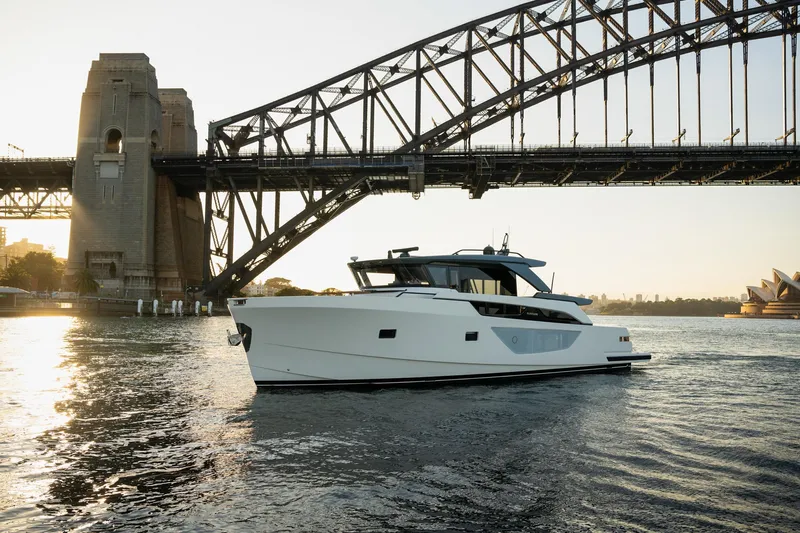Bgx63 Yacht Photos Pics 2024 Bluegame BGX63 yacht cruising under iconic bridge at sunset.