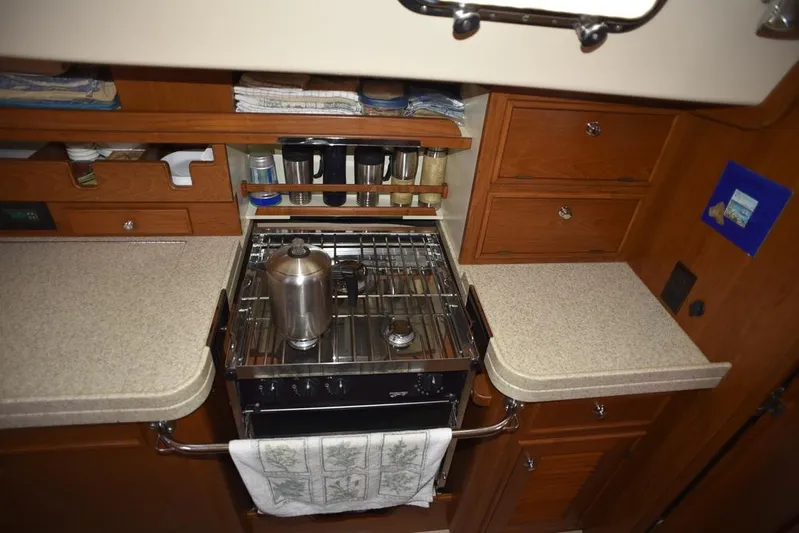 Watermark Lll Yacht Photos Pics 2005 Island Packet 445 yacht kitchen with stove, countertops, and wooden cabinetry.