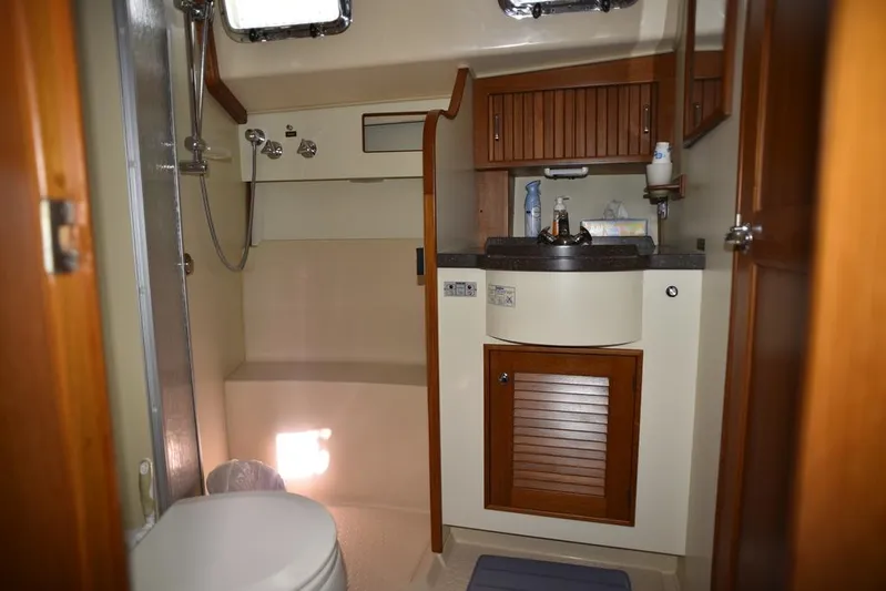 Watermark Lll Yacht Photos Pics 2005 Island Packet 445 yacht bathroom with shower, sink, and wooden cabinetry.