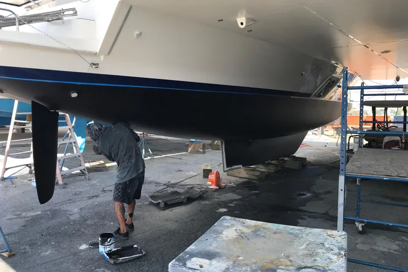 Flip Flops Yacht Photos Pics Person painting the hull of a 2017 Leopard 48 yacht in a shipyard.