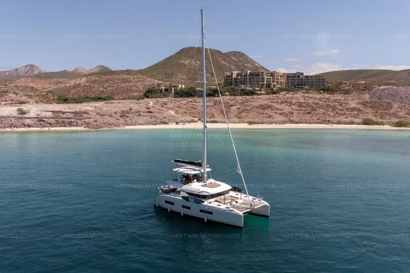  Yacht Photos Pics 2023 Lagoon 55 catamaran anchored in serene bay with mountainous backdrop.