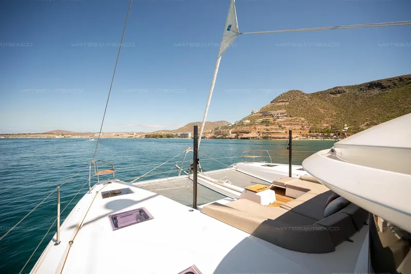  Yacht Photos Pics Luxurious 2023 Lagoon 55 yacht sailing near scenic coastal landscape.