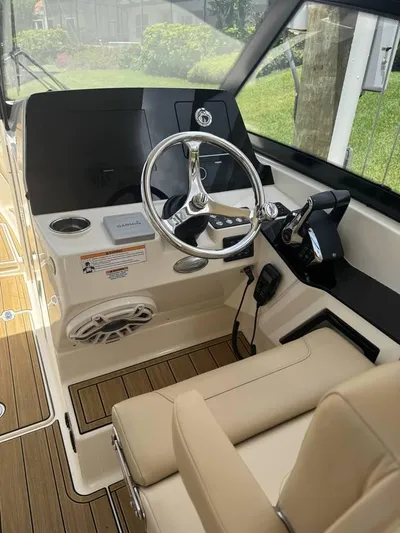  Yacht Photos Pics 2023 Scout 277 Dorado boat cockpit with steering wheel and beige seating.