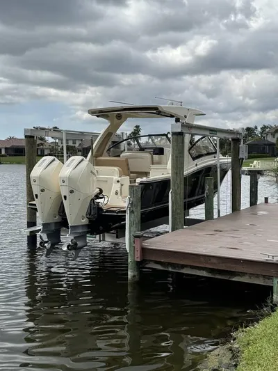 Yacht Photos Pics 2023 Scout 277 Dorado boat docked on a lift by a lake under cloudy skies.