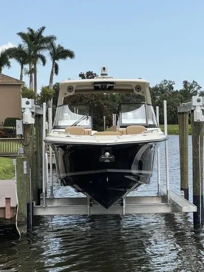  Yacht Photos Pics 2023 Scout 277 Dorado boat on lift, surrounded by water and palm trees.