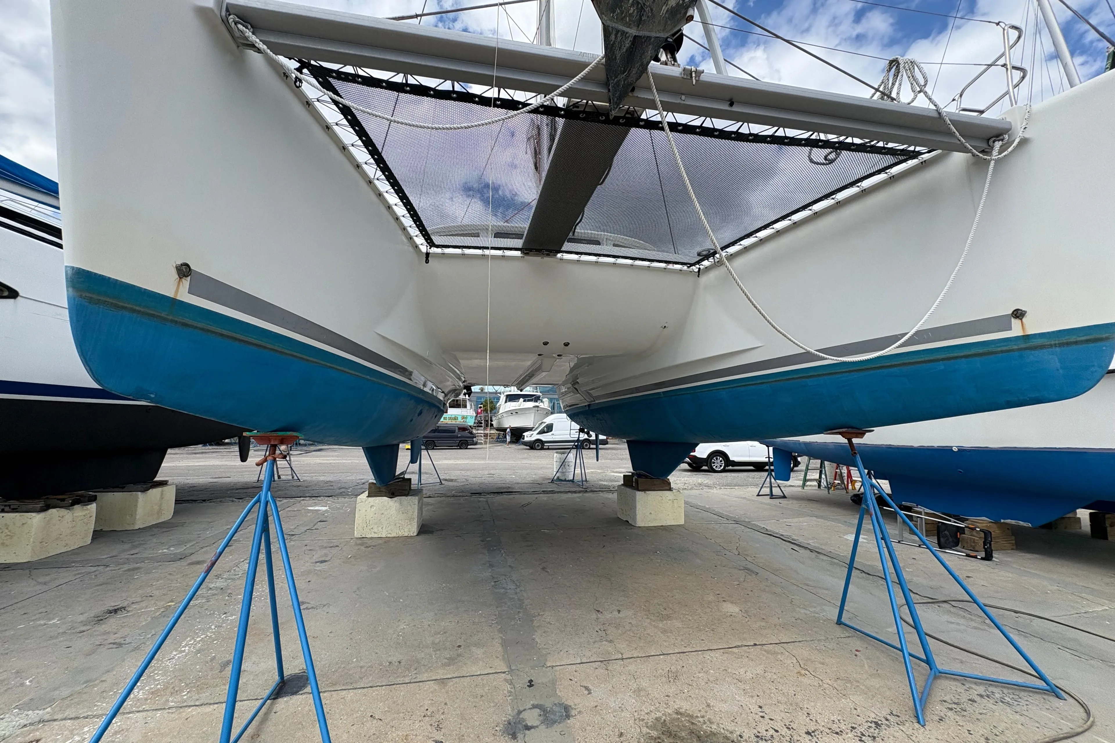 2004 Lagoon 380 catamaran on stands, showcasing hull and underbody in a boatyard.