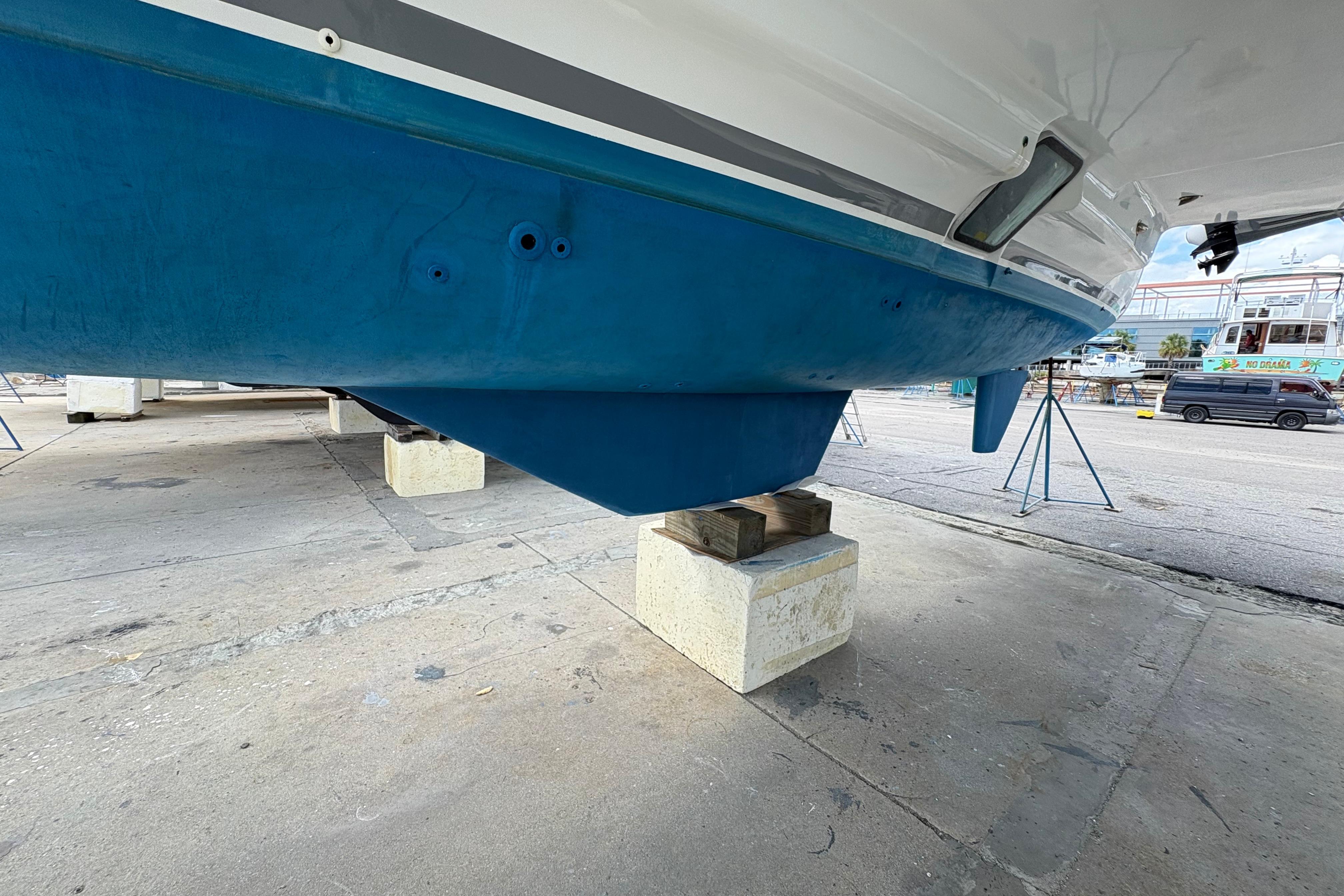 2004 Lagoon 380 catamaran hull on dry dock, showcasing blue underside and support blocks.