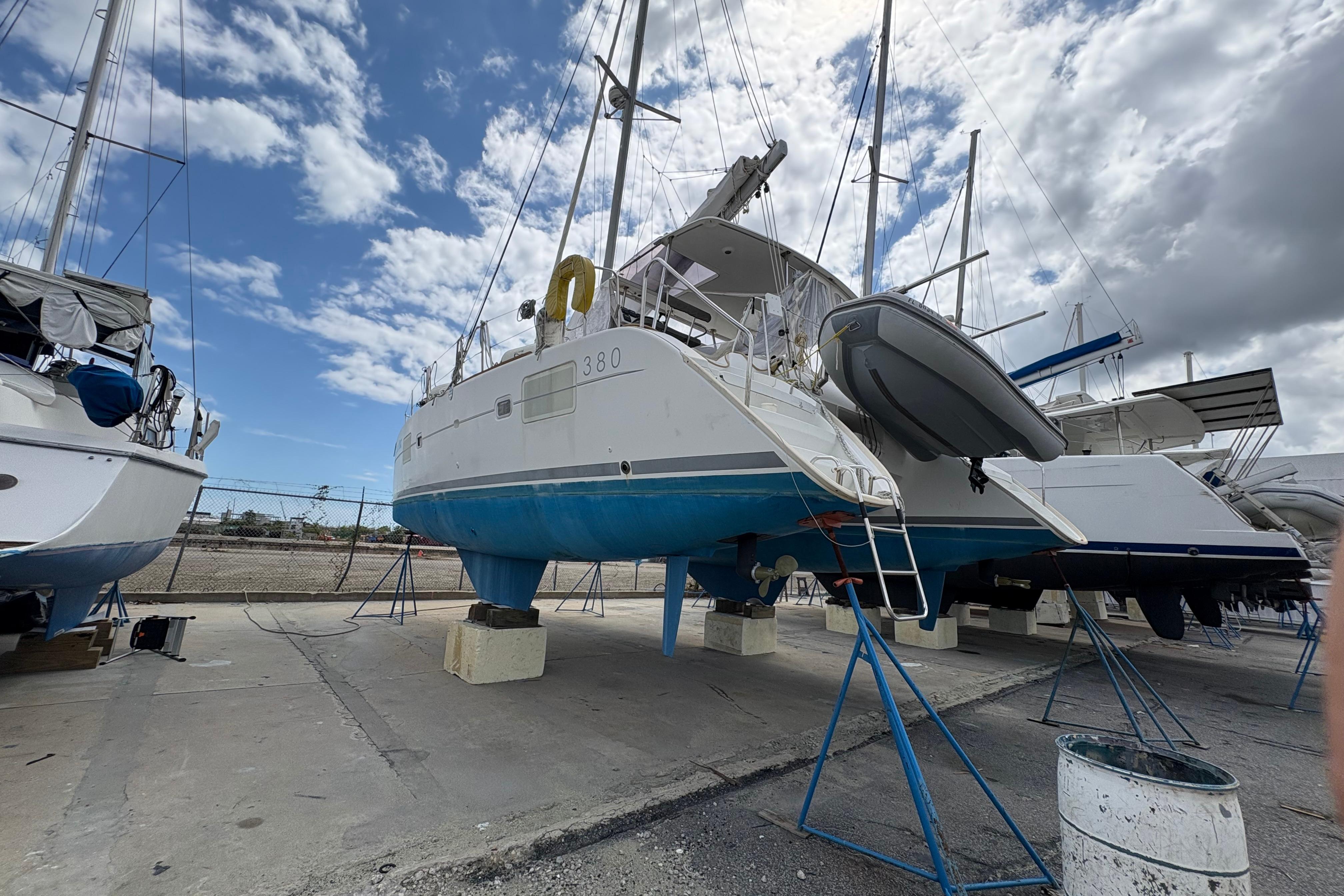 2004 Lagoon 380 catamaran on dry dock under a partly cloudy sky.