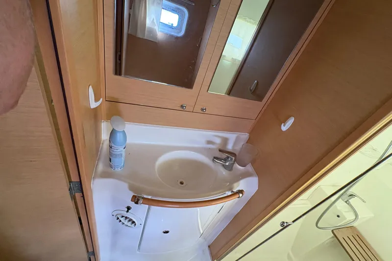 Toucan Deux Yacht Photos Pics Compact bathroom in 2004 Lagoon 380 catamaran with sink, mirror, and shower area.