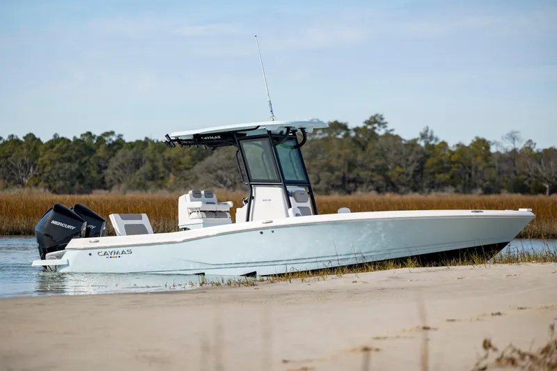  Yacht Photos Pics 2024 Caymas 281 HB boat docked on a sandy shore with scenic background.
