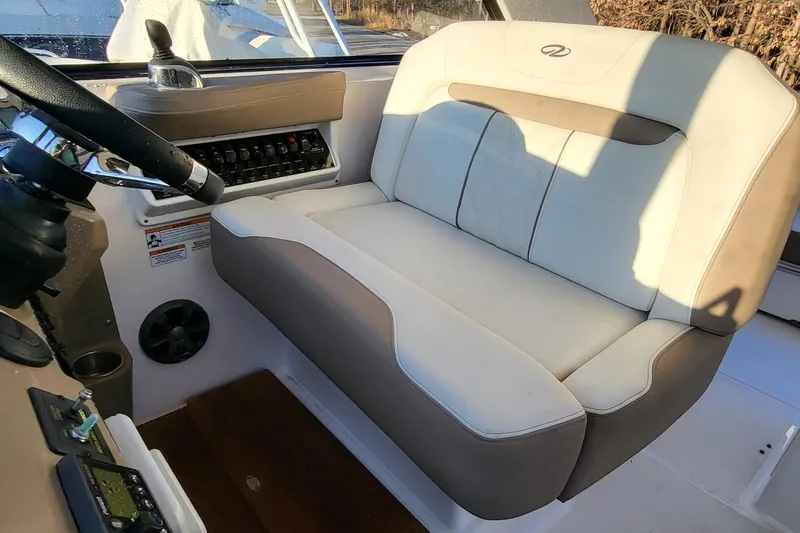  Yacht Photos Pics Captain's seat in 2018 Regal 35 Sport Coupe boat cockpit, featuring control panel and steering wheel.