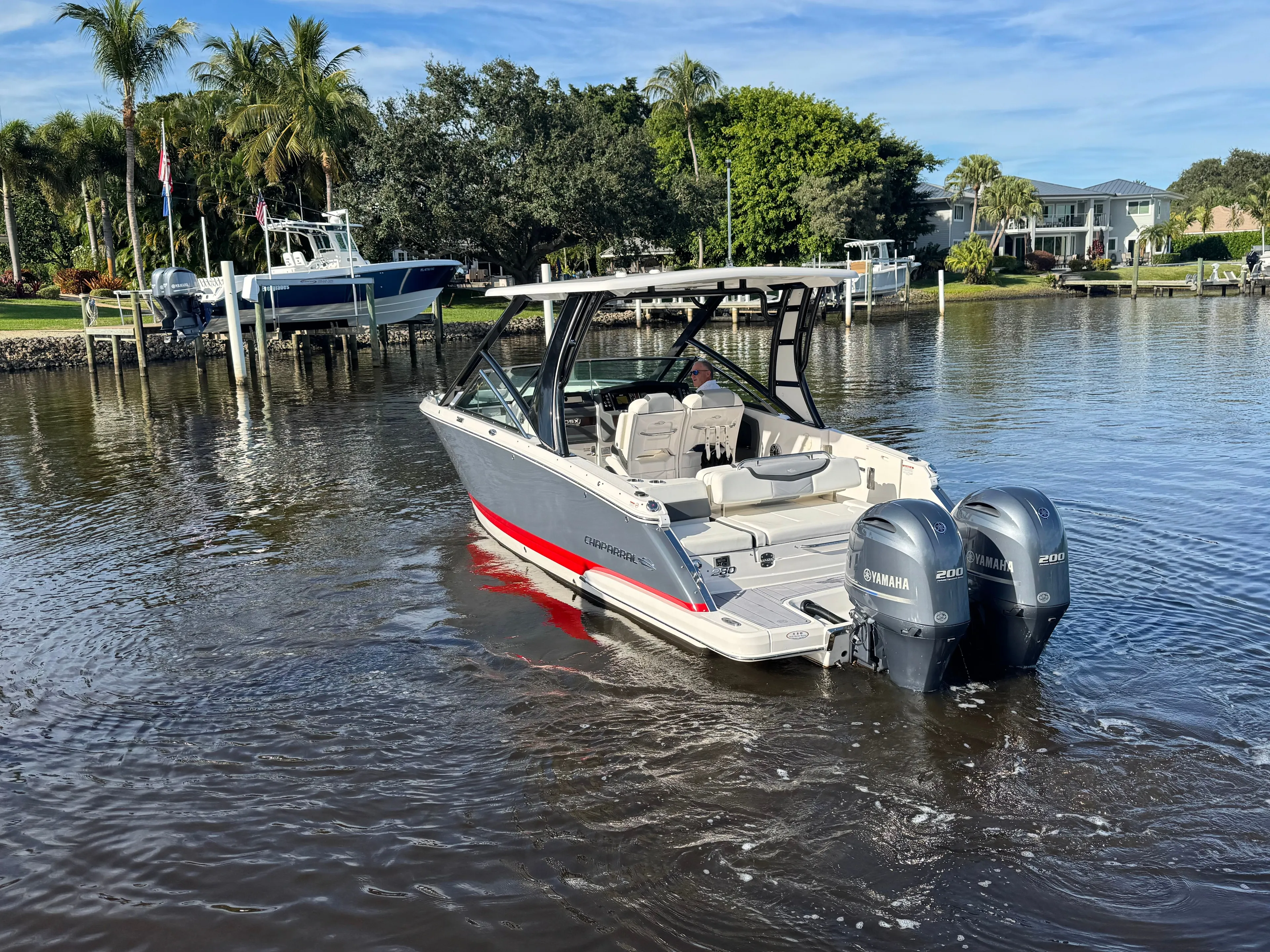  Yacht Photos Pics 2023 Chaparral 280 OSX boat on calm water with palm trees in background.