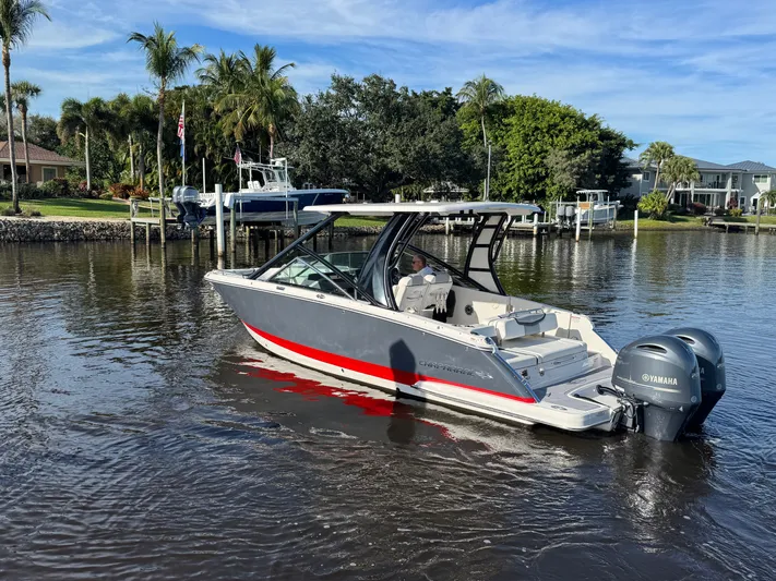  Yacht Photos Pics 2023 Chaparral 280 OSX boat on calm water with palm trees in background.