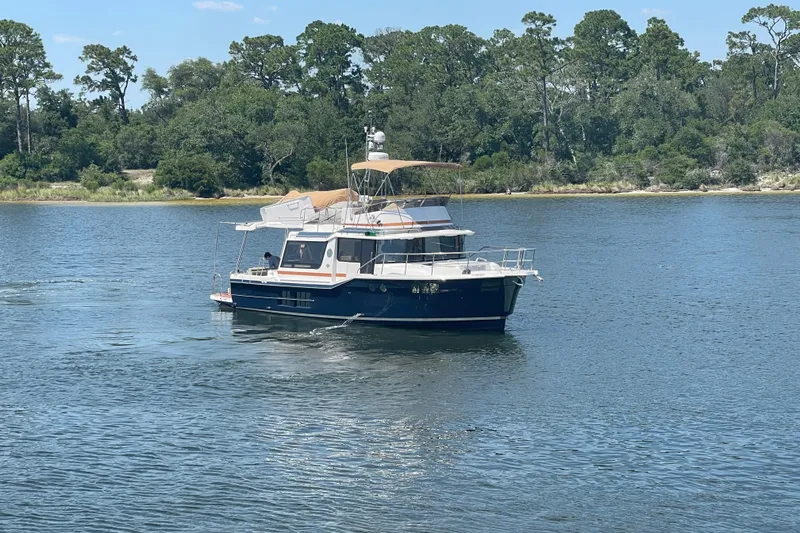  Yacht Photos Pics 2024 Ranger Tugs R-43 CB cruising on a serene lake with lush greenery.
