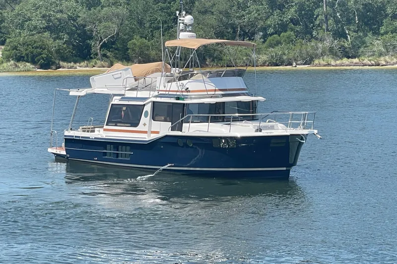  Yacht Photos Pics 2024 Ranger Tugs R-43 CB yacht on a serene lake with lush greenery.