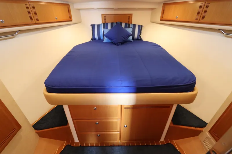  Yacht Photos Pics Luxurious cabin interior of 2007 Cabo 40 Hardtop Express with blue bedding and wooden storage.