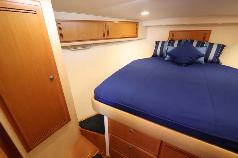  Yacht Photos Pics Luxurious cabin interior of 2007 Cabo 40 Hardtop Express with blue bedding and wooden storage.