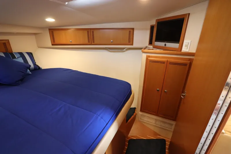 Yacht Photos Pics Interior cabin of 2007 Cabo 40 Hardtop Express with blue bedding and wooden cabinetry.