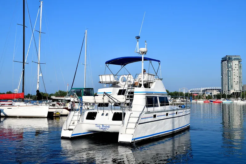 Two Buoys Yacht Photos Pics 2002 PDQ 32 Power Catamaran docked in a marina with cityscape background.
