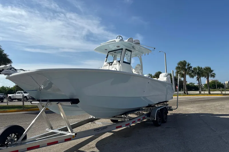  Yacht Photos Pics 2025 Freeman 28 boat on trailer under clear blue sky, parked near palm trees.