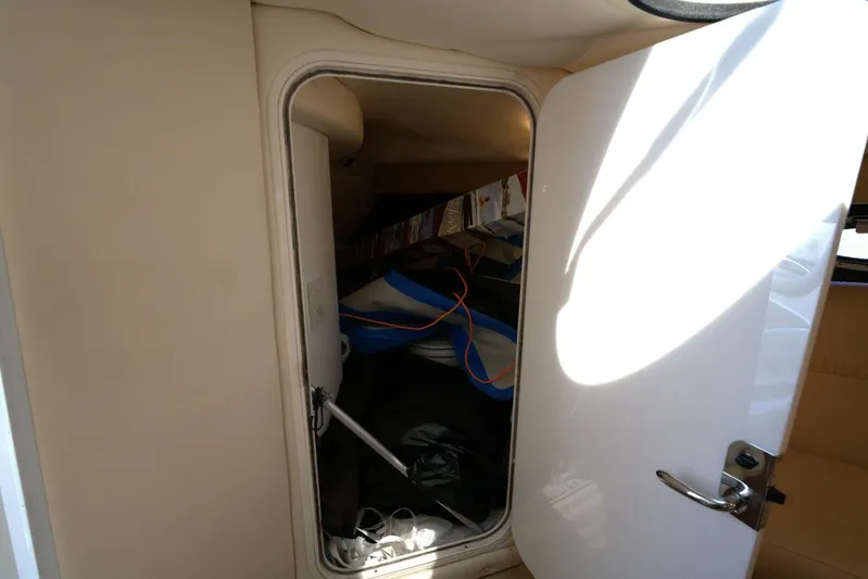  Yacht Photos Pics Storage compartment inside a 2005 Cobalt 343 boat, partially open door, revealing interior items.