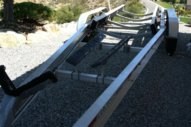  Yacht Photos Pics Boat trailer for 2005 Cobalt 343 on gravel driveway, surrounded by greenery.