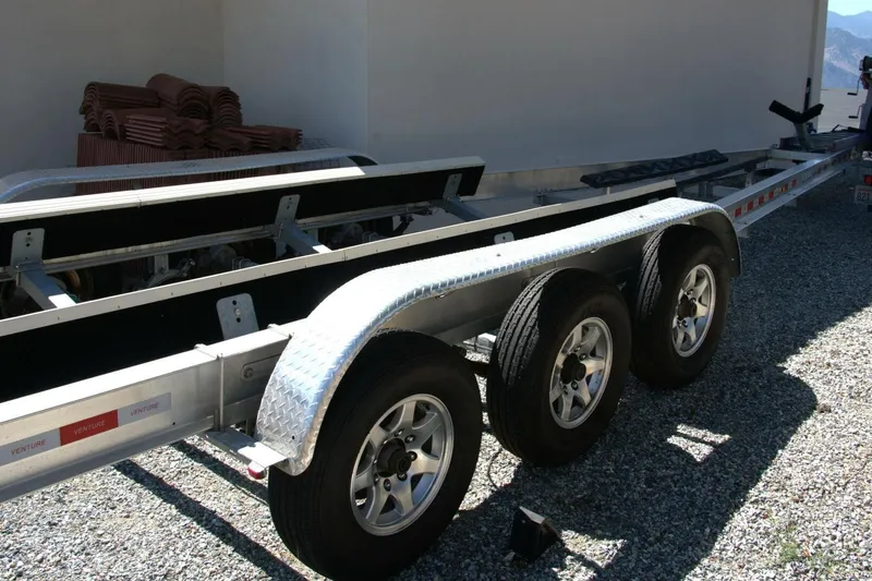  Yacht Photos Pics Triple-axle boat trailer for 2005 Cobalt 343, parked on gravel.