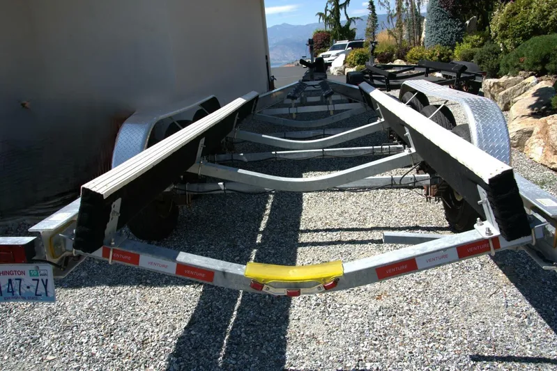  Yacht Photos Pics Trailer for 2005 Cobalt 343 boat on gravel driveway, surrounded by greenery.