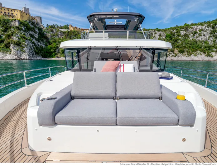  Yacht Photos Pics 2025 Beneteau Grand Trawler 62 yacht with luxurious deck seating, scenic coastal backdrop.