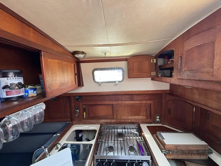 Pacific Seacraft Crealock 37 Yacht Photos Pics Interior of 1995 Pacific Seacraft Crealock 37 sailboat kitchen with wooden cabinetry and stove.