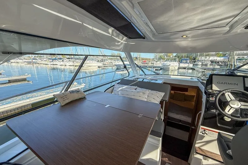  Yacht Photos Pics Interior of 2024 Beneteau Antares 9 boat with table and helm, docked at marina.