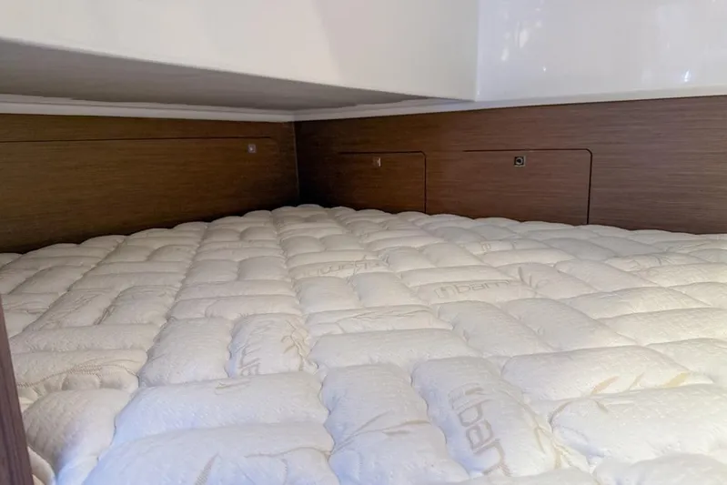  Yacht Photos Pics 2024 Beneteau Antares 9 cabin interior with plush mattress and wooden paneling.