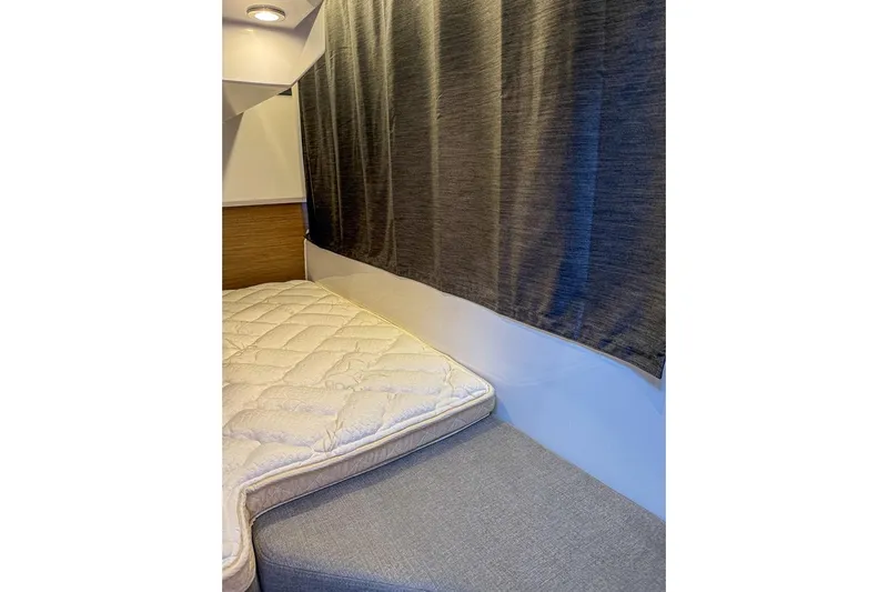  Yacht Photos Pics 2024 Beneteau Antares 9 cabin interior with bed and curtain.