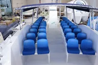 Olbap TR12 Open 2025 boat with blue seating, spacious deck, and canopy in a workshop setting.
