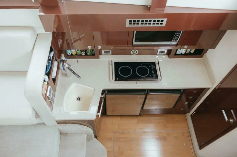 The Green Squirrel Yacht Photos Pics 2010 Sea Ray 390 Sedan Bridge kitchen with stove, sink, and microwave in compact layout.