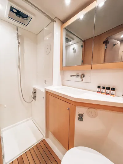  Yacht Photos Pics 2019 Lagoon 450 s yacht bathroom with shower, wooden accents, and toiletries.