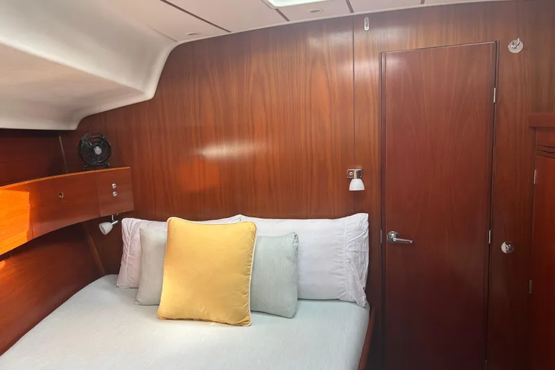 Unbound Yacht Photos Pics Cozy cabin interior of 2001 Beneteau First 47.7 yacht with wooden paneling and bed.