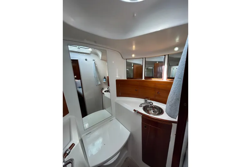 Unbound Yacht Photos Pics Bathroom interior of 2001 Beneteau First 47.7 yacht, featuring sink, mirror, and wooden cabinetry.