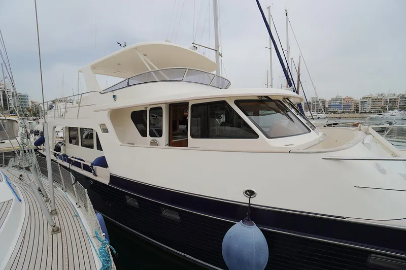 Defly Yacht Photos Pics Luxury 2009 Marlow 61E yacht docked in marina, showcasing sleek design and spacious deck.