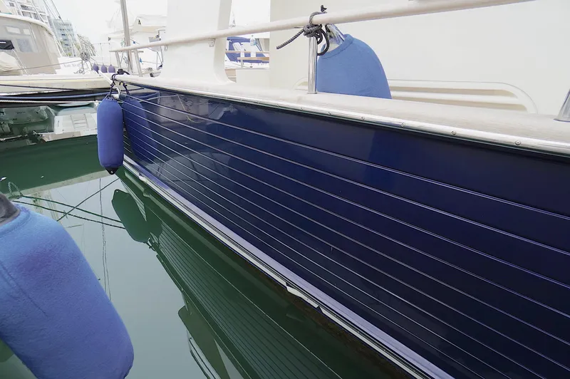 Defly Yacht Photos Pics Side view of a 2009 Marlow 61E yacht with blue fenders in a marina.